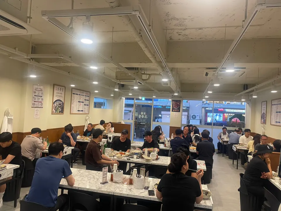 오봉집 천장 조명이 밝은 홀에서 손님들이 식사하는 모습